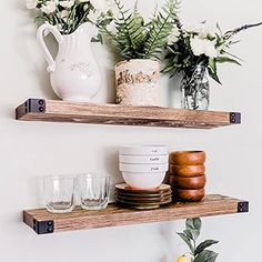 two wooden shelves holding dishes and vases on top of each other with flowers in the background