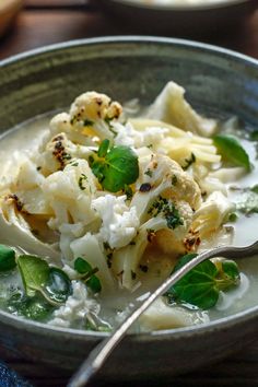 a close up of a bowl of food with broccoli and cauliflower