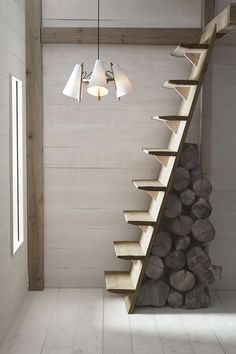 a staircase made out of wood with lights hanging from the ceiling and logs stacked on the floor