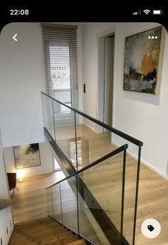 a staircase with glass railing and wood flooring