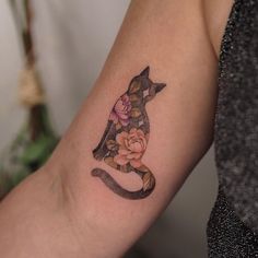 a woman's arm with a cat and flowers tattoo on the left side of her arm