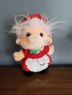 a stuffed animal with white hair and red dress