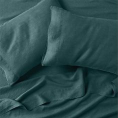 a bed with green sheets and pillows on it