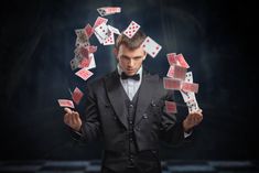 a man in a tuxedo juggling cards into the air with his hands