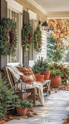 the porch is decorated for christmas with wreaths and potted plants on the bench