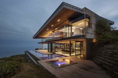 a house with a pool in front of it at night, overlooking the ocean and mountains