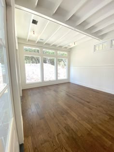 an empty room with wood floors and white walls