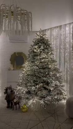 a christmas tree in the middle of a living room with lights on and decorations hanging from the ceiling