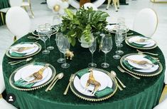 the table is set with green velvet and gold place settings, including white dinnerware