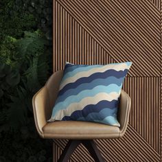 a blue and white pillow sitting on top of a chair in front of a wall