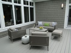 an outdoor living area with couches, chairs and coffee table on the decking