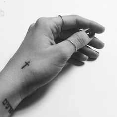 a person's hand with a cross tattoo on the middle of their left arm