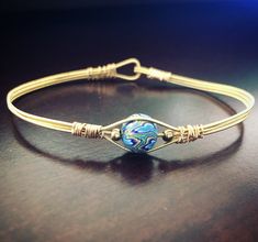 Gold guitar string bracelet with bead of blue mixture of colors Beaded Guitar, Guitar Bracelet, Gold Guitar, Guitar String Jewelry, Mountain Dulcimer, Guitar String Bracelet, String Jewelry, Guitar Strings, String Bracelet