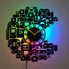 a clock made out of video game controllers on a white wall with rainbow light in the background