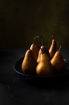 four pears on a black plate against a dark background