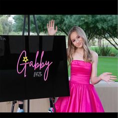 a girl in a pink dress is holding up a sign that says gabby haze