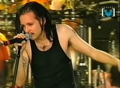 a man with dreadlocks singing into a microphone in front of a drum set