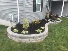 landscaping in front of a house with flowers and plants on the side of the house