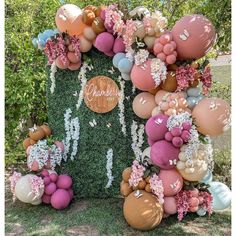 a house made out of balloons and flowers in the grass with a sign that says grandma on it