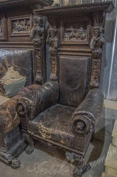 an old leather chair with ornate carvings on the back and arm rests in front of a mirror