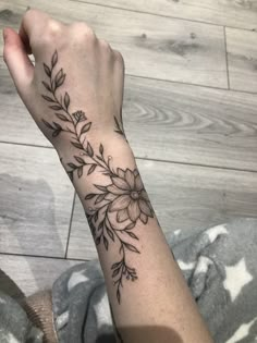 a woman's arm with flowers and leaves tattooed on the left side of her wrist