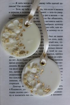 two white ornaments with gold glitters on top of an open page in a book