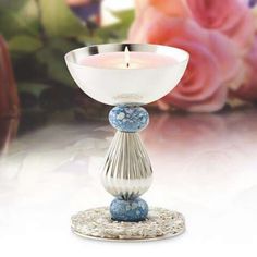 a white and blue candle holder with flowers in the background