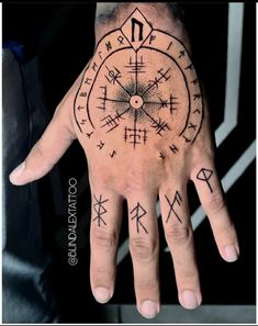 a man's hand with an ancient compass tattoo on his left palm and two arrows in the middle