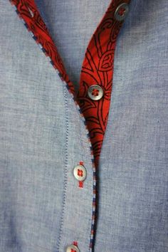 a man wearing a blue shirt and red tie with buttons on his lapel collar