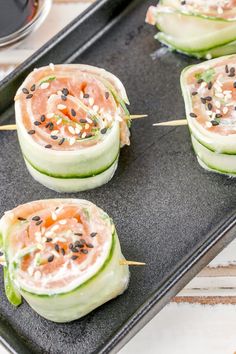 cucumber wrapped in salmon and topped with black sesame seeds on a baking sheet