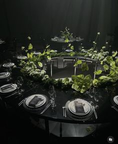 the table is set with plates, silverware and greenery on it for an elegant dinner