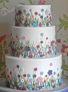 three tiered cake decorated with flowers and grass