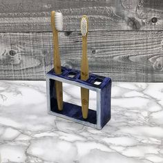 two toothbrushes in a holder on a marble counter