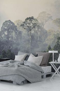 a large bed sitting in front of a forest wallpapered with trees and fog