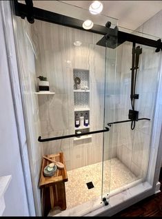 a walk in shower sitting next to a wooden table and white tiled walls with black trim