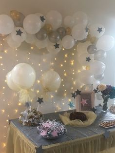 a table topped with balloons and cake next to a wall filled with stars on it