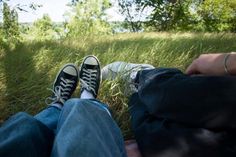 two people sitting in the grass with their feet up