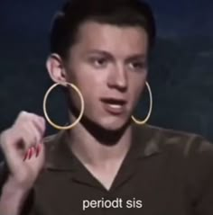 a man wearing large gold hoop earrings on his face in front of a dark background