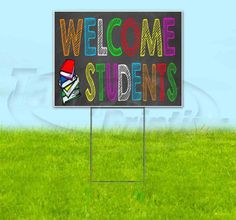 a welcome sign in the middle of a field with grass and blue sky behind it