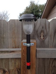 a lamp on top of a wooden post next to a fence