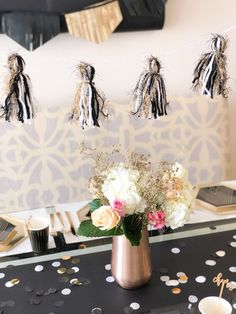 a black and white table cloth with flowers in a vase on it, hanging from the ceiling