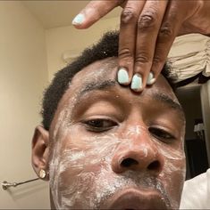 a woman is shaving her face with white clay on her forehead and hands above her head