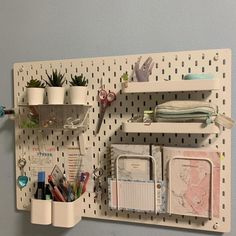 a peg board with some office supplies hanging on it's side and two shelves