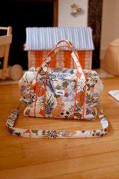 a purse sitting on top of a wooden floor next to a doll house with furniture in the background