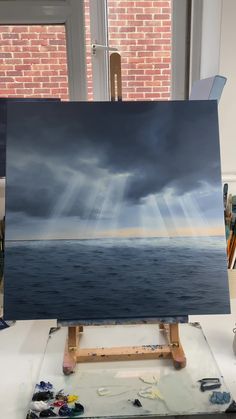 an easel with a painting on it in front of a window