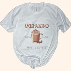 Indulge in the rich, creamy delight of our "Mochaccino" tee, a tribute to coffee lovers everywhere. This t-shirt captures the essence of the beloved mocha beverage with a stylized graphic of a steaming cup adorned with whipped cream and a sprinkle of cocoa. Rendered in warm mocha hues, this design blends the art of coffee with the world of fashion, making it a perfect pick for casual outings or cozy cafe visits. Crafted from a soft, breathable fabric, it promises comfort and style in equal measu Coffee Boutique, Coffee Clothes, Barista Outfits, Vanilla Frappuccino, Barista Style, Coffee Outfit, Sassy Tee, Outfits Unique, Wide Neck Sweatshirt