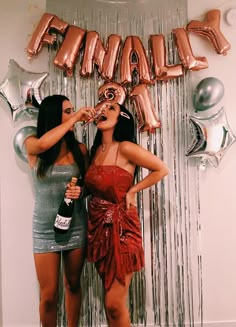 two women standing next to each other in front of balloons