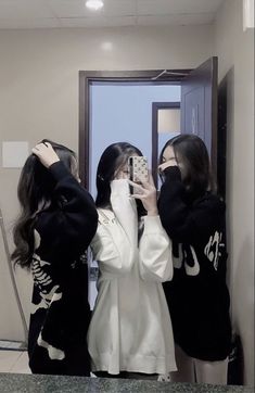 two women standing in front of a mirror taking pictures