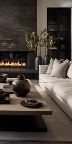 a living room with white couches and a fire place in the wall behind it