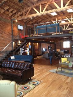 a living room filled with lots of furniture and a loft style ceiling mounted high above